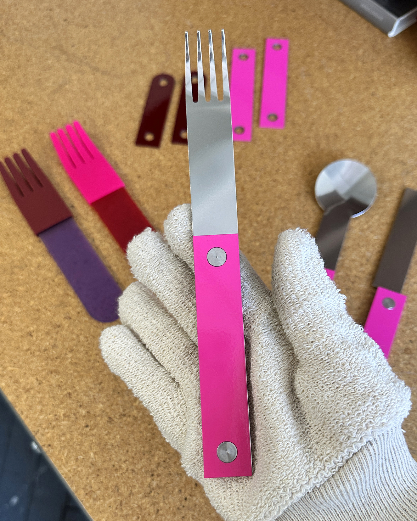 forks-plus-flatware-pink-handle-studio-shot Gloved hand holding stainless steel fork with pink riveted handles