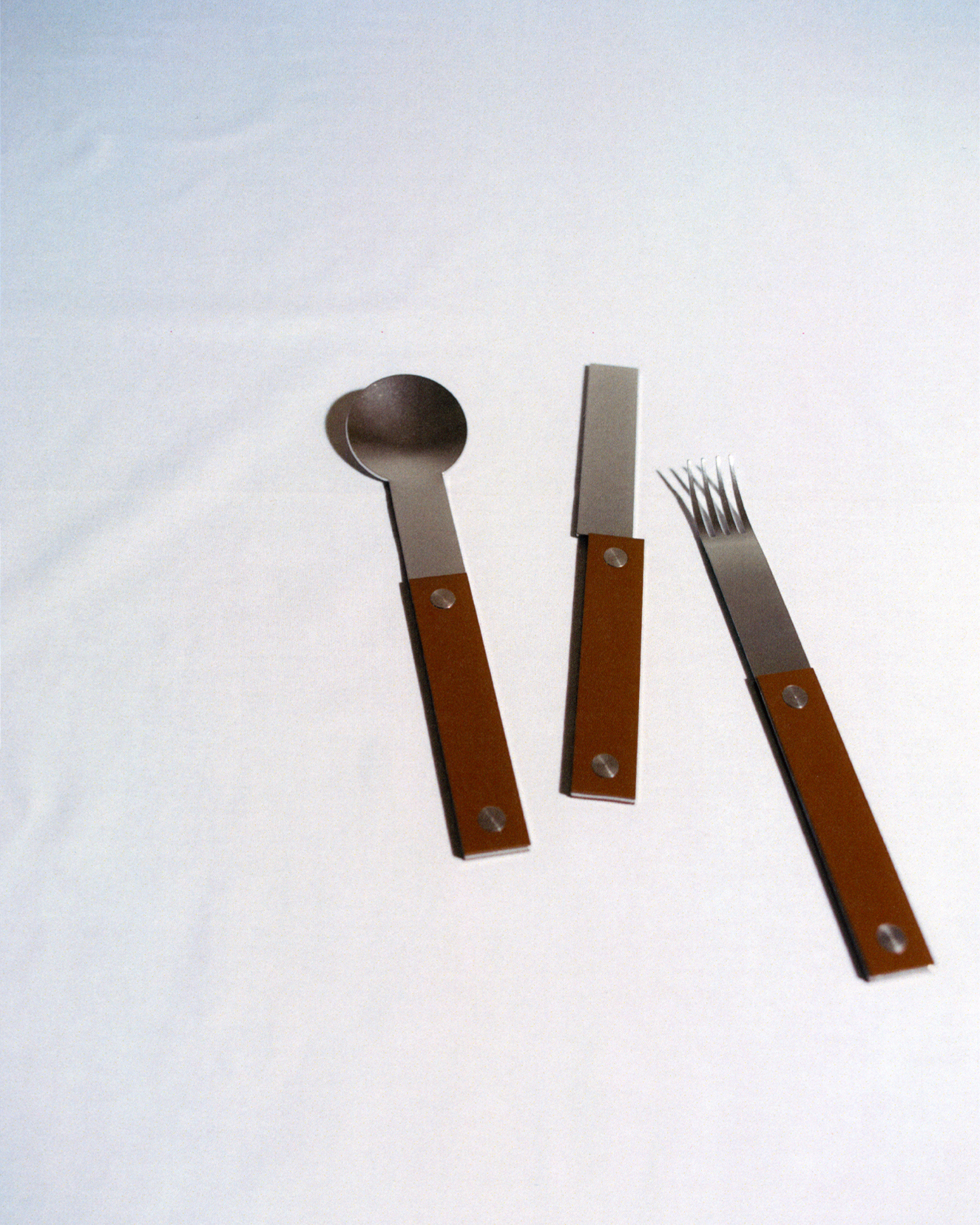 forks-plus-flatware-trio-brown-handles-white-tablecloth Trio of stainless steel flatware with brown handles on white tablecloth