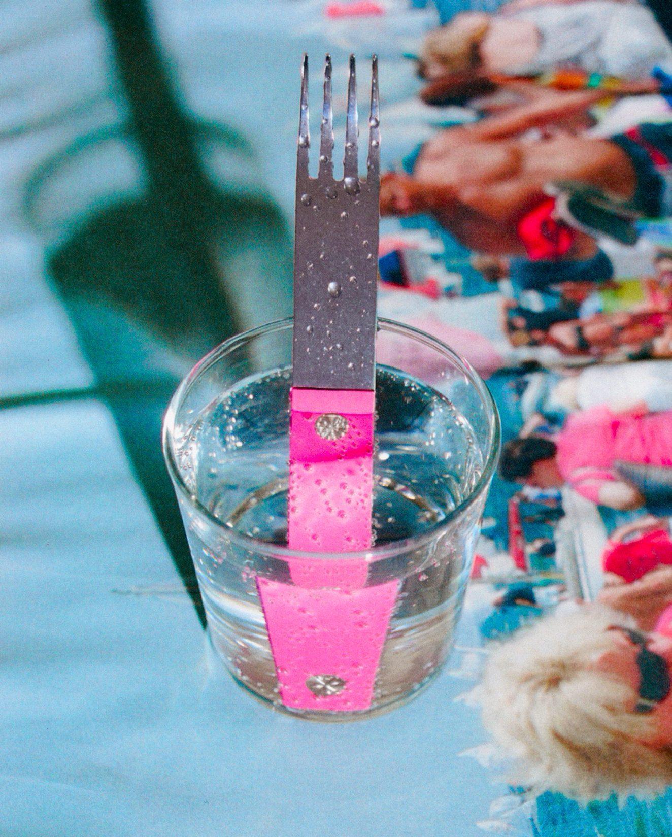 forks-plus-closeup-blue-placemat-pink-fork Pink powder-coated stainless steel fork in a cup on a placemat, close-up