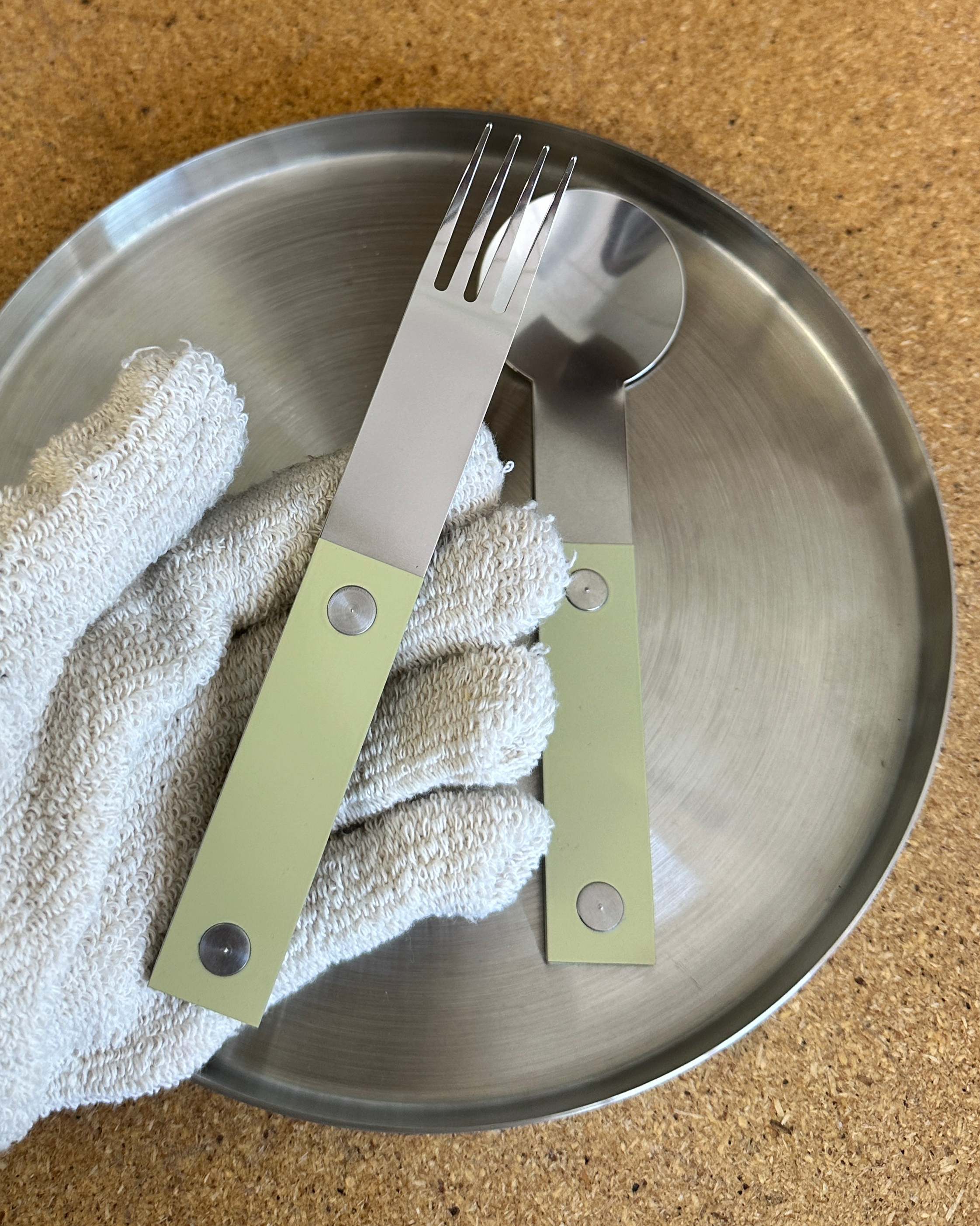 forks-plus-closeup-butter-handle-stainless-steel Gloved hand holding small stainless steel fork with butter-colored riveted handle