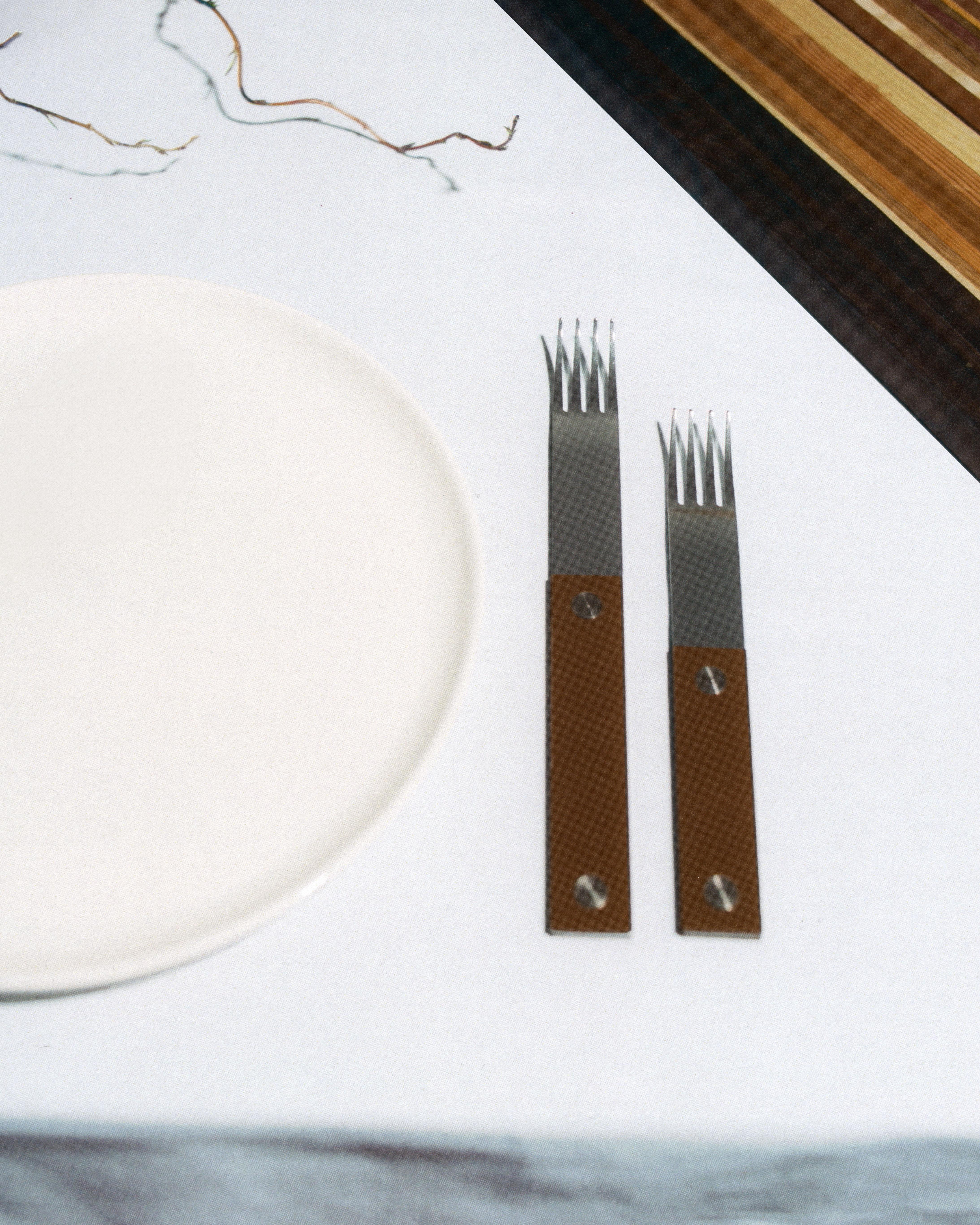 forks-plus-stainless-forks-chocolate-handle-place-setting Stainless steel forks with brown handles beside a white plate and striped cutting board