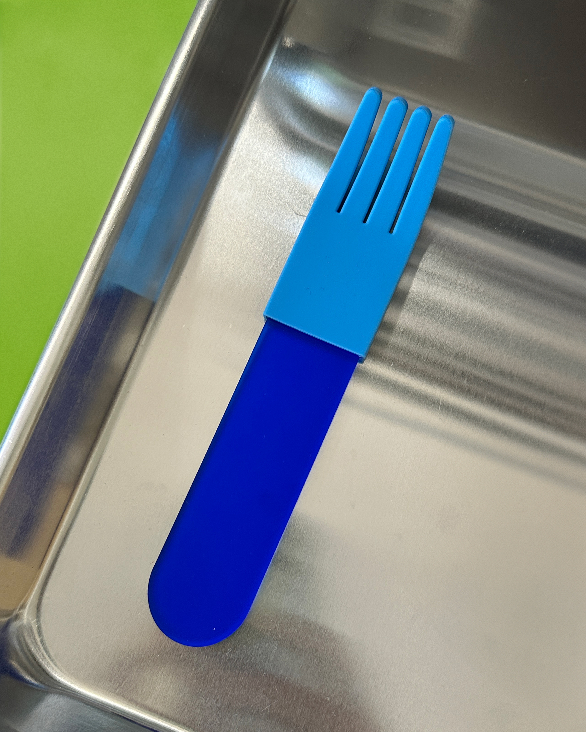 forks-plus-blue-acrylic-fork-blue-sleeve-steel-tray Blue acrylic fork with light blue silicone sleeve sitting on stainless steel tray