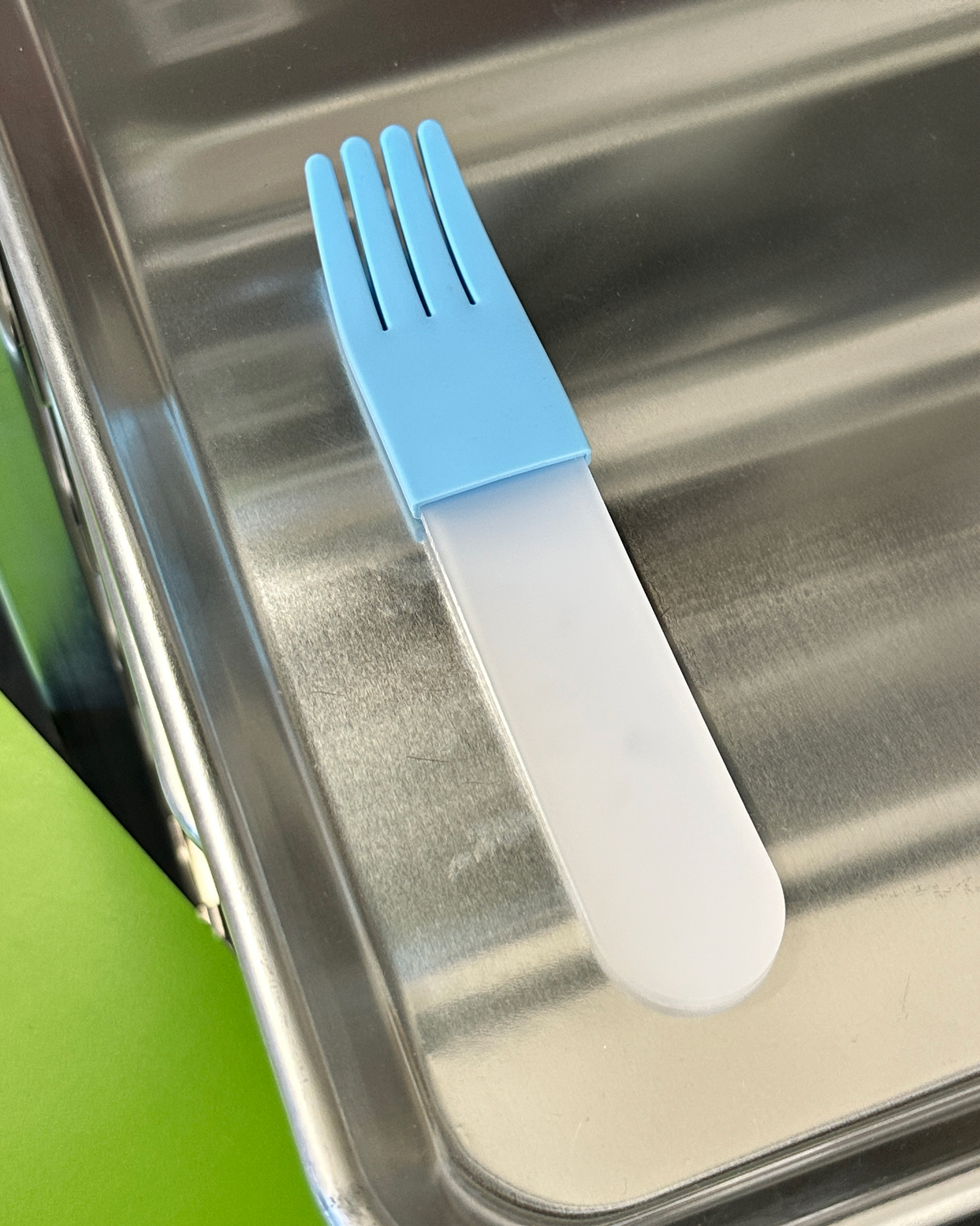 forks-plus-white-acrylic-fork-blue-sleeve-steel-tray Transparent white acrylic fork with light blue silicone sleeve sitting on stainless steel tray