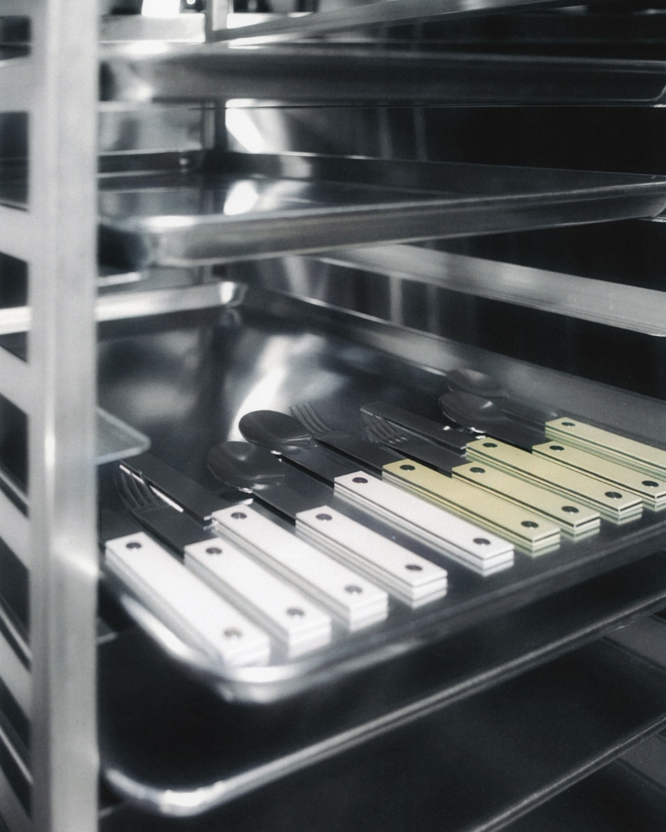 forks-plus-flatware-butter-almond-sets-speed-rack Butter and almond-colored 5-piece flatware sets on stainless steel tray sitting on a speed rack